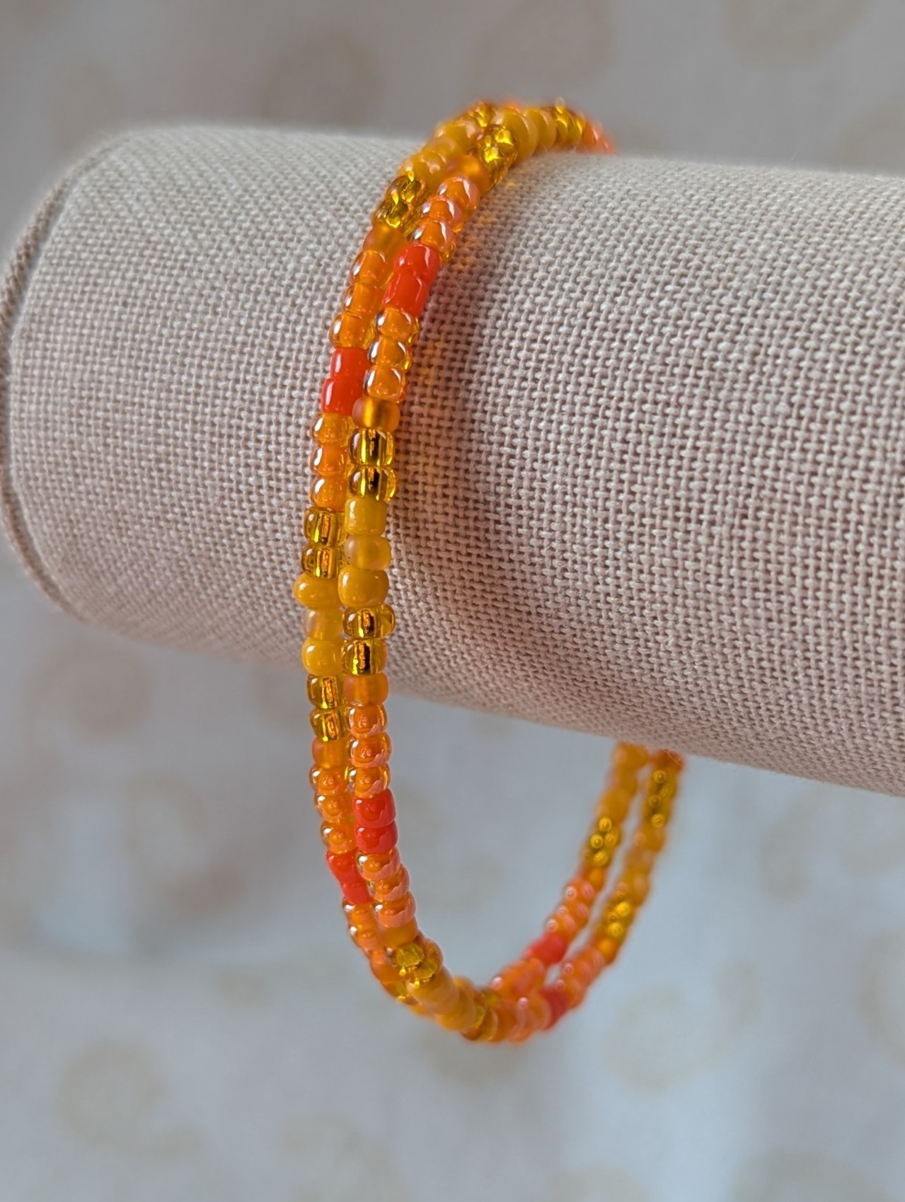 Orange memory wire bracelet with multiple shades and textures of orange glass beads, stretchy design with no clasp.