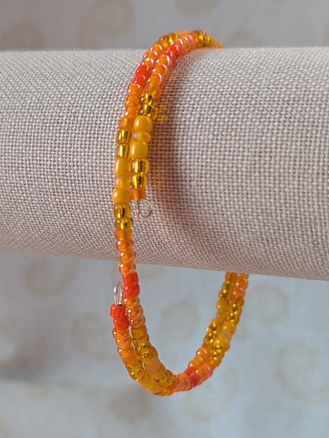 Orange memory wire bracelet with multiple shades and textures of orange glass beads, stretchy design with no clasp.