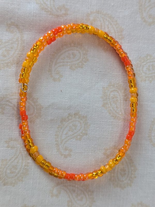 Orange memory wire bracelet with multiple shades and textures of orange glass beads, stretchy design with no clasp.