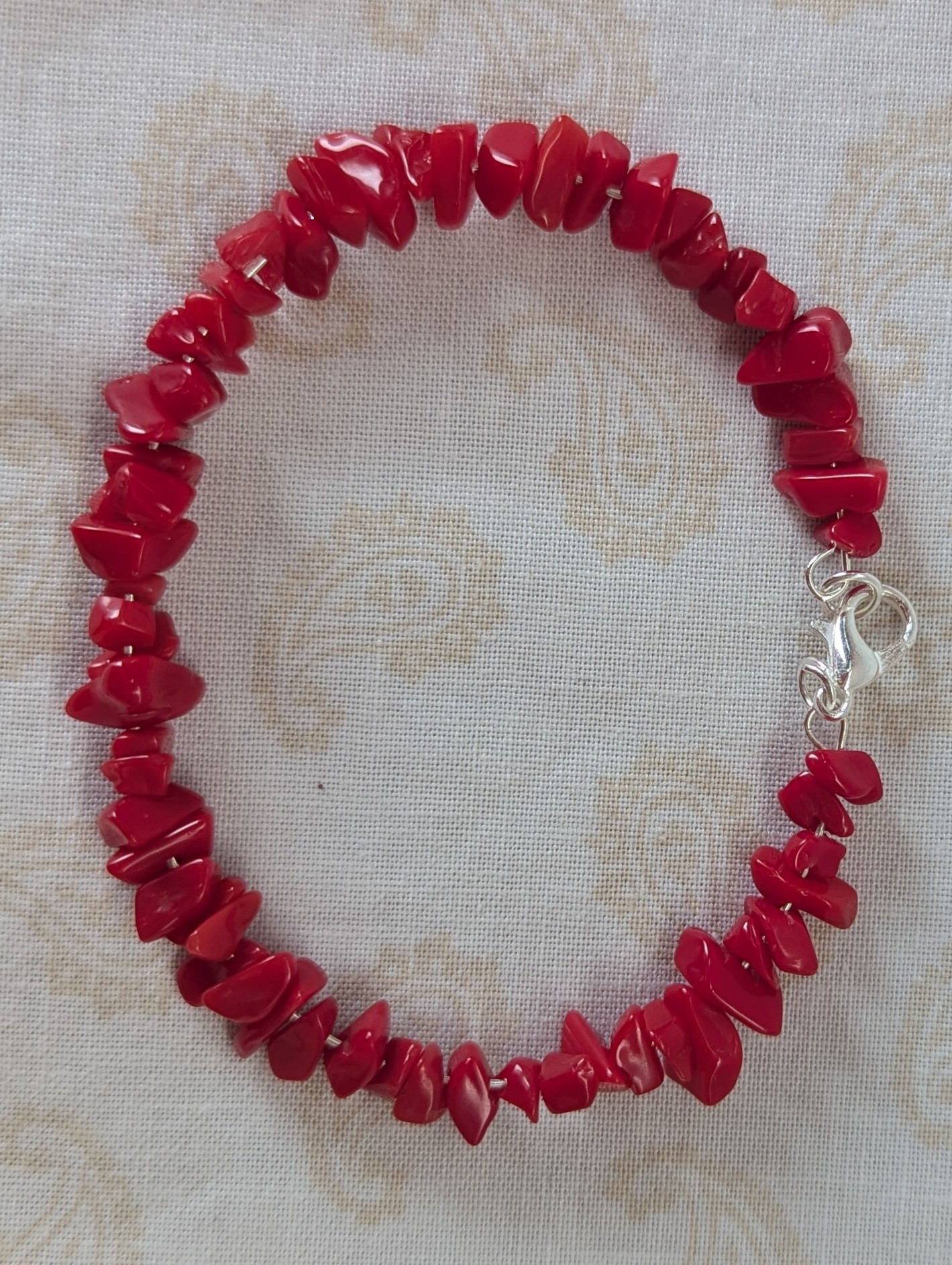 Red stone memory wire bracelet with polished cherry red chip stone beads and a silver-colored lobster clasp closure.