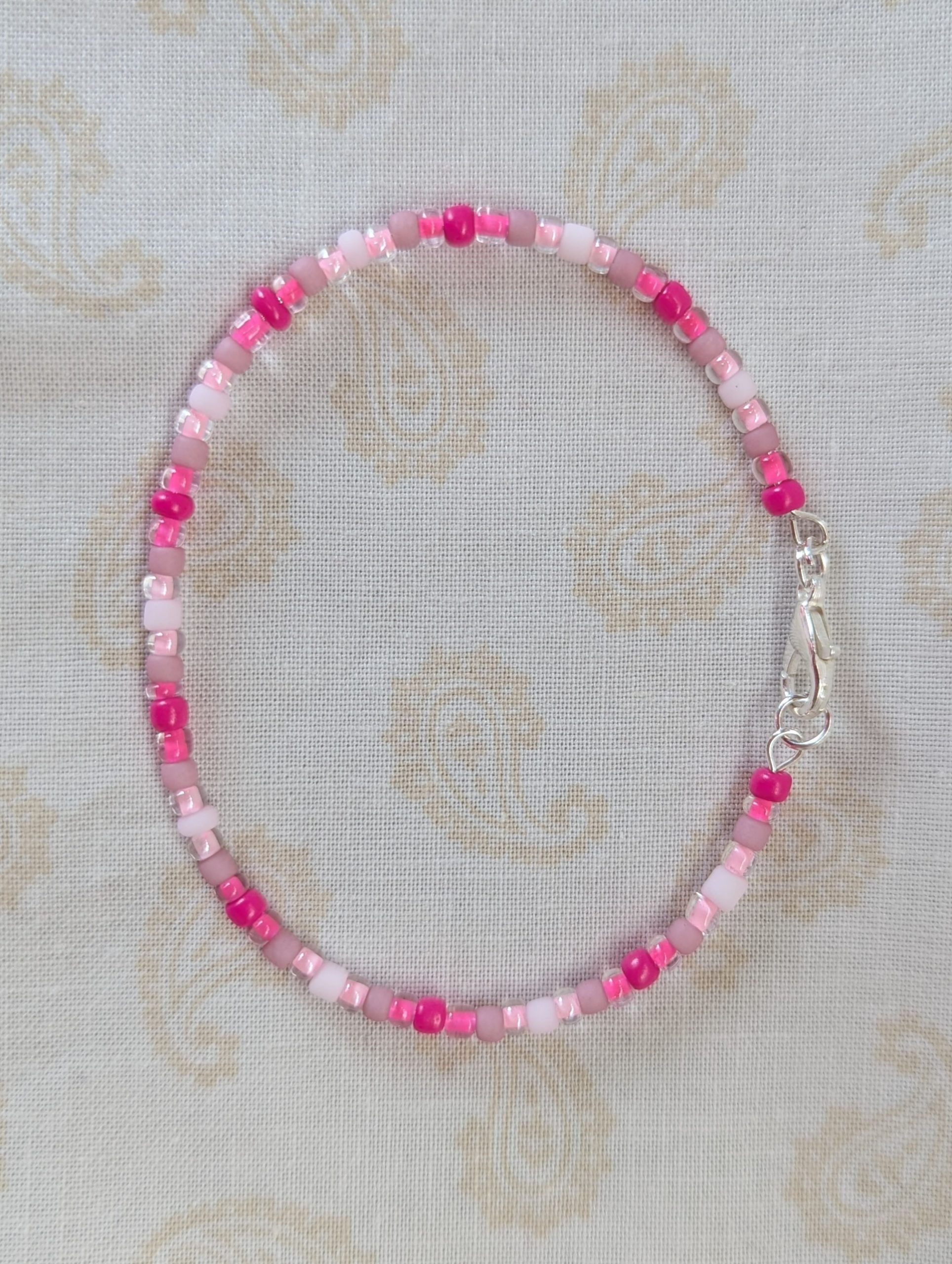 Pink memory wire bracelet with mixed pink beads in various textures and hues, finished with a silver-colored lobster clasp.