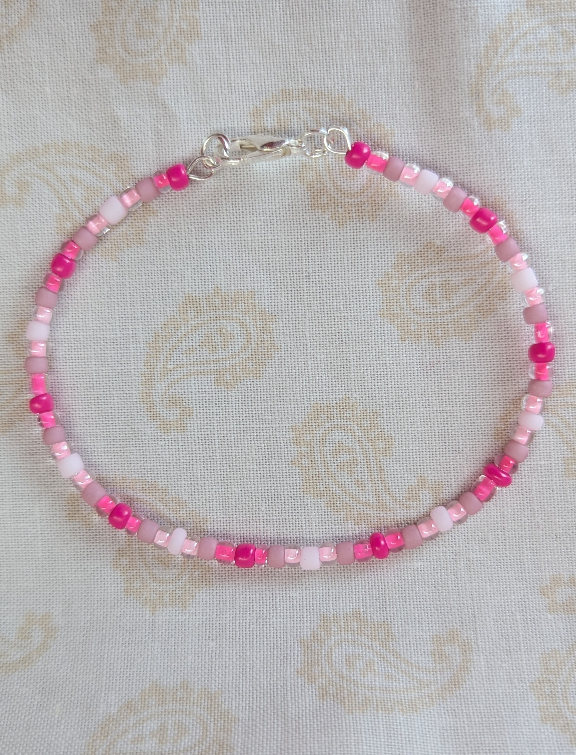 Pink memory wire bracelet with mixed pink beads in various textures and hues, finished with a silver-colored lobster clasp.