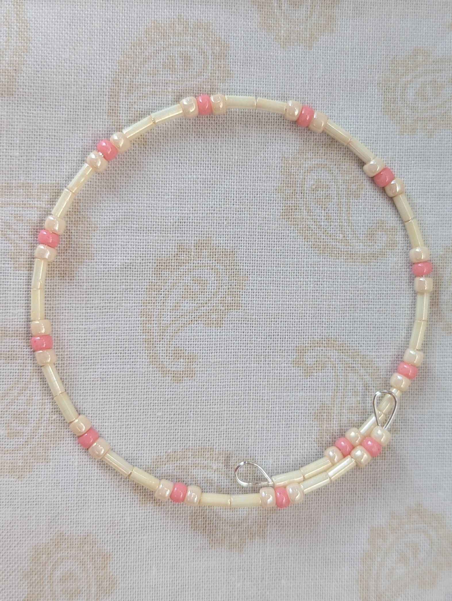 Cream and pink beaded bracelet with memory wire featuring ivory tube beads, cream round beads, and ballet pink accents with stretch overlap closure