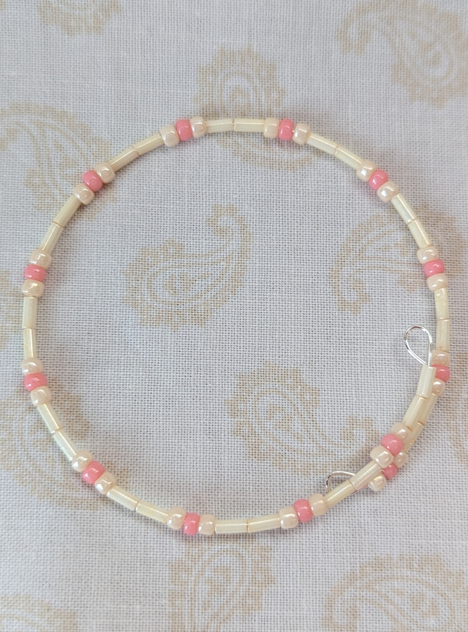 Cream and pink beaded bracelet with memory wire featuring ivory tube beads, cream round beads, and ballet pink accents with stretch overlap closure