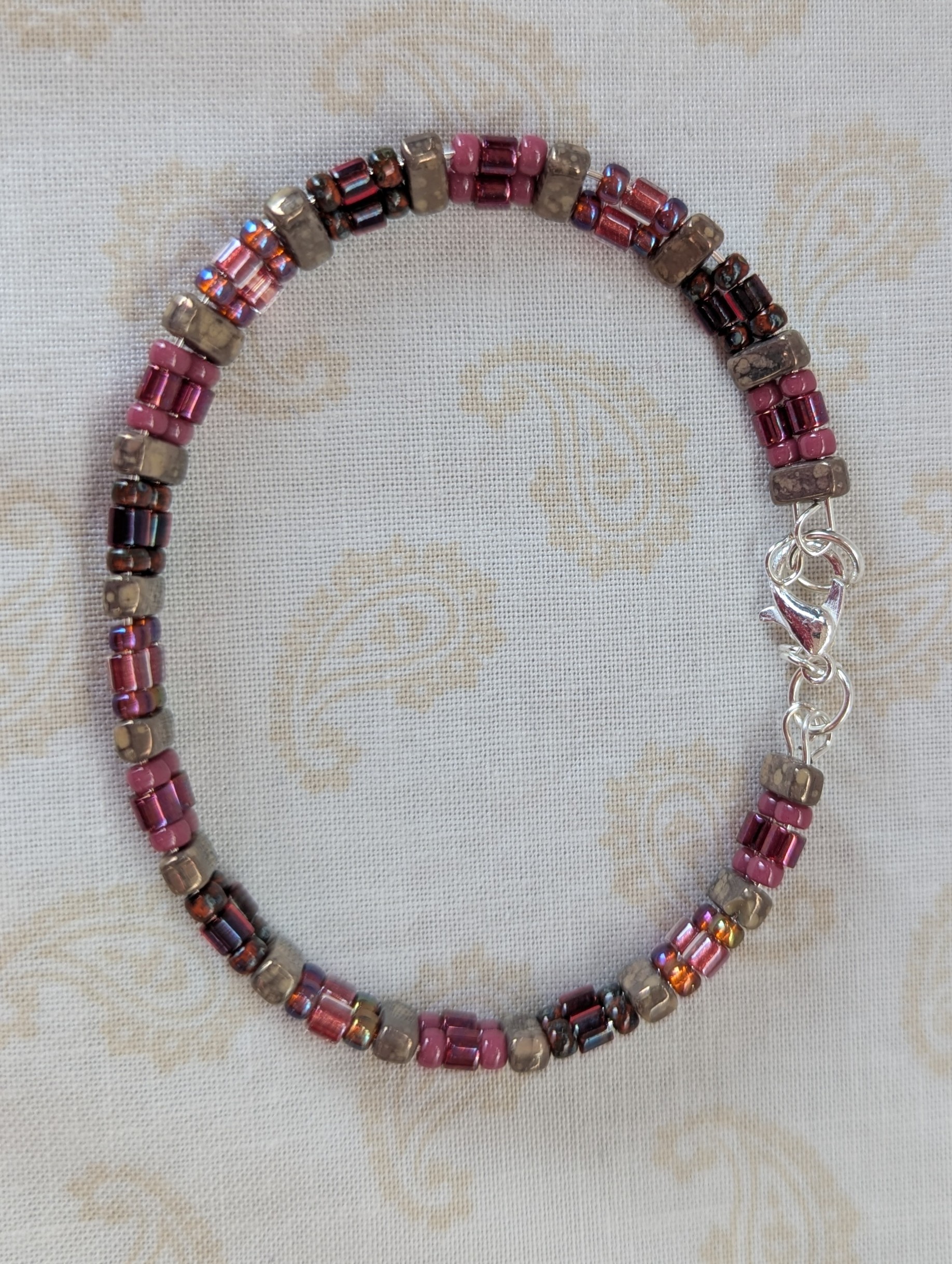 Double-strand memory wire bracelet with rose mauve, garnet, and taupe rectangular stone beads, finished with a silver lobster clasp.