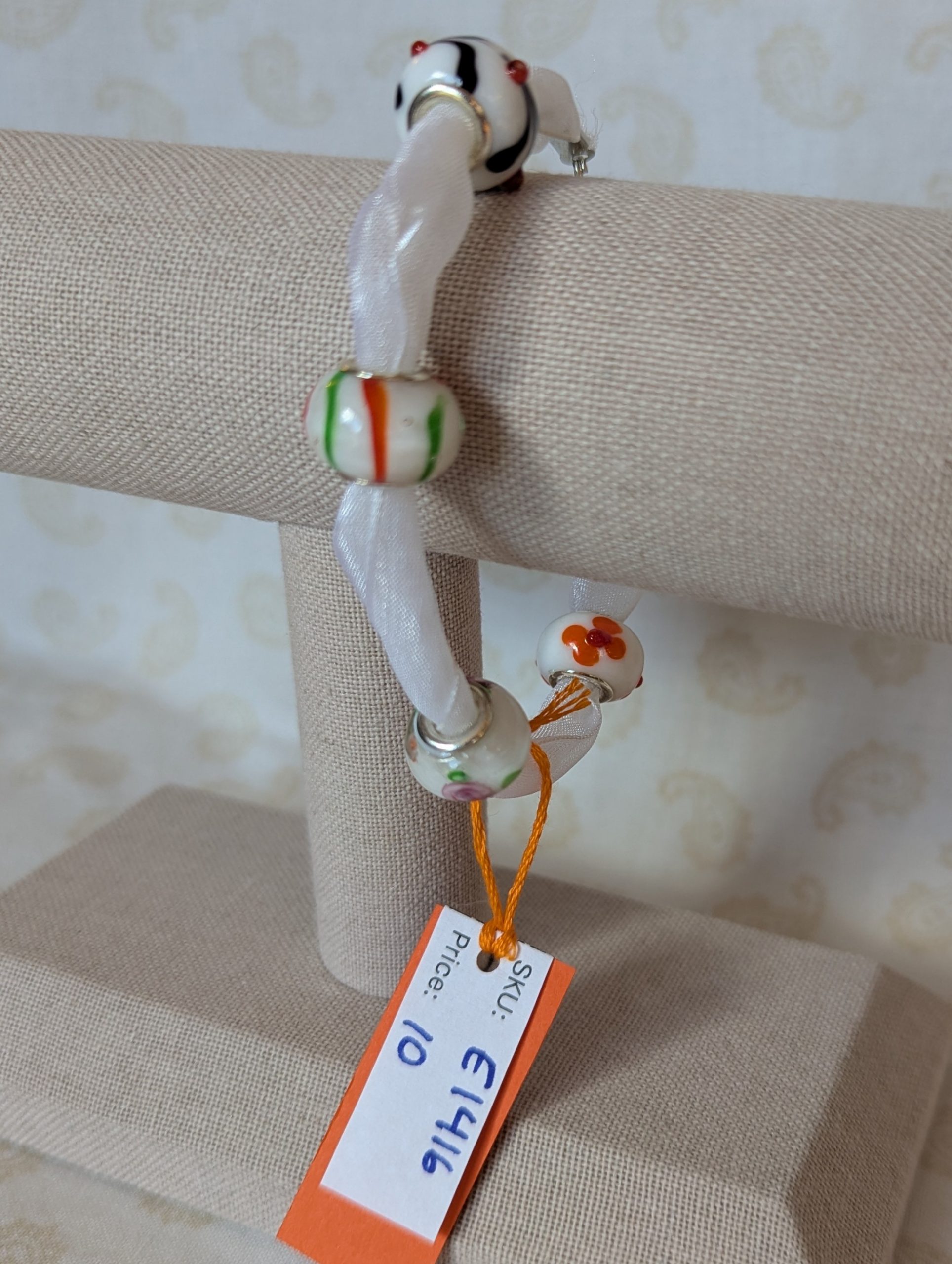 Petal Drift White Lampwork Ribbon Bracelet with sheer white ribbon, four decorative glass beads with colorful floral and stripe details, and lobster clasp