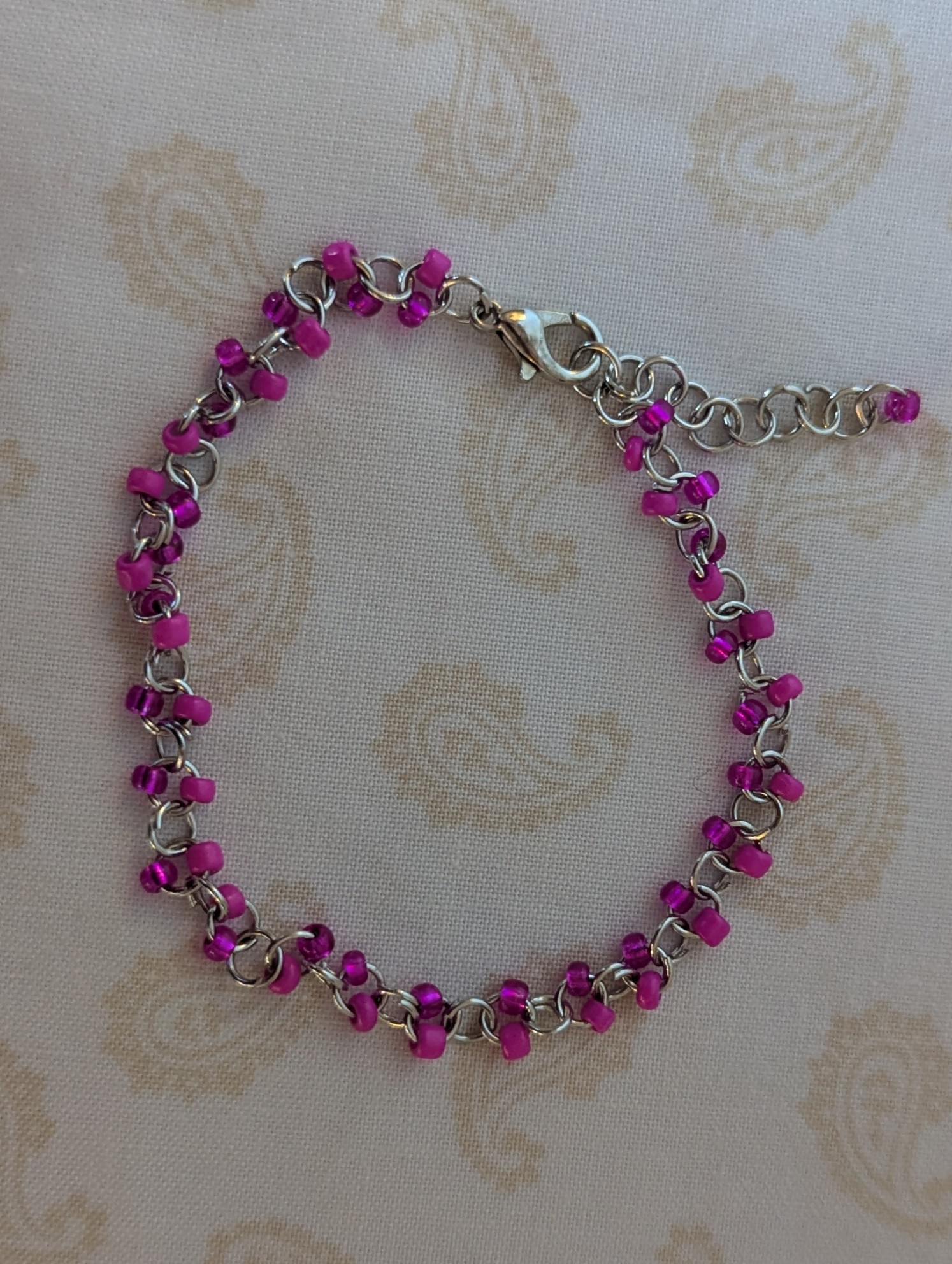 Steel-colored chain bracelet with alternating hot pink and silver-lined translucent pink glass beads and a lobster clasp.