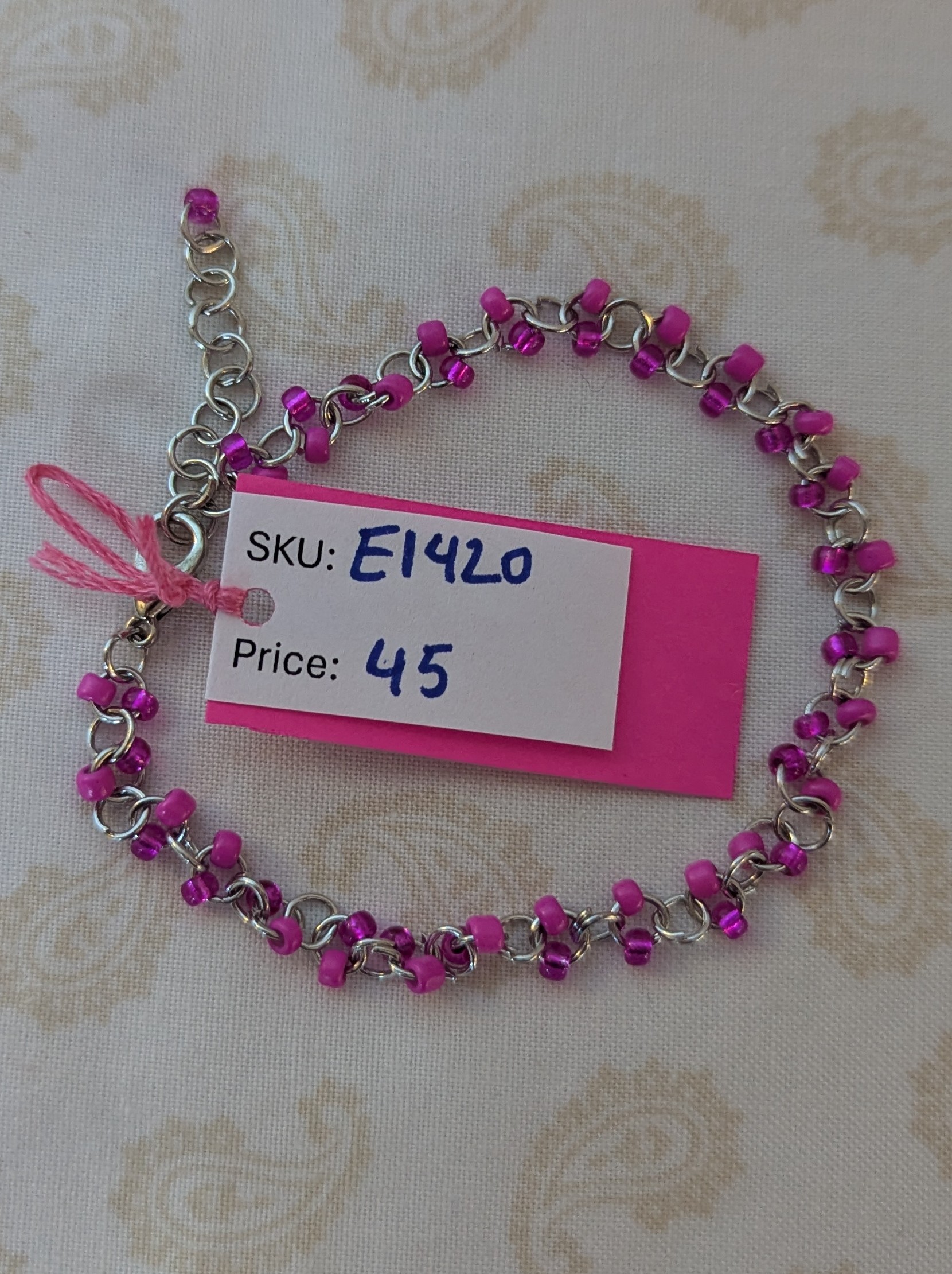 Steel-colored chain bracelet with alternating hot pink and silver-lined translucent pink glass beads and a lobster clasp.