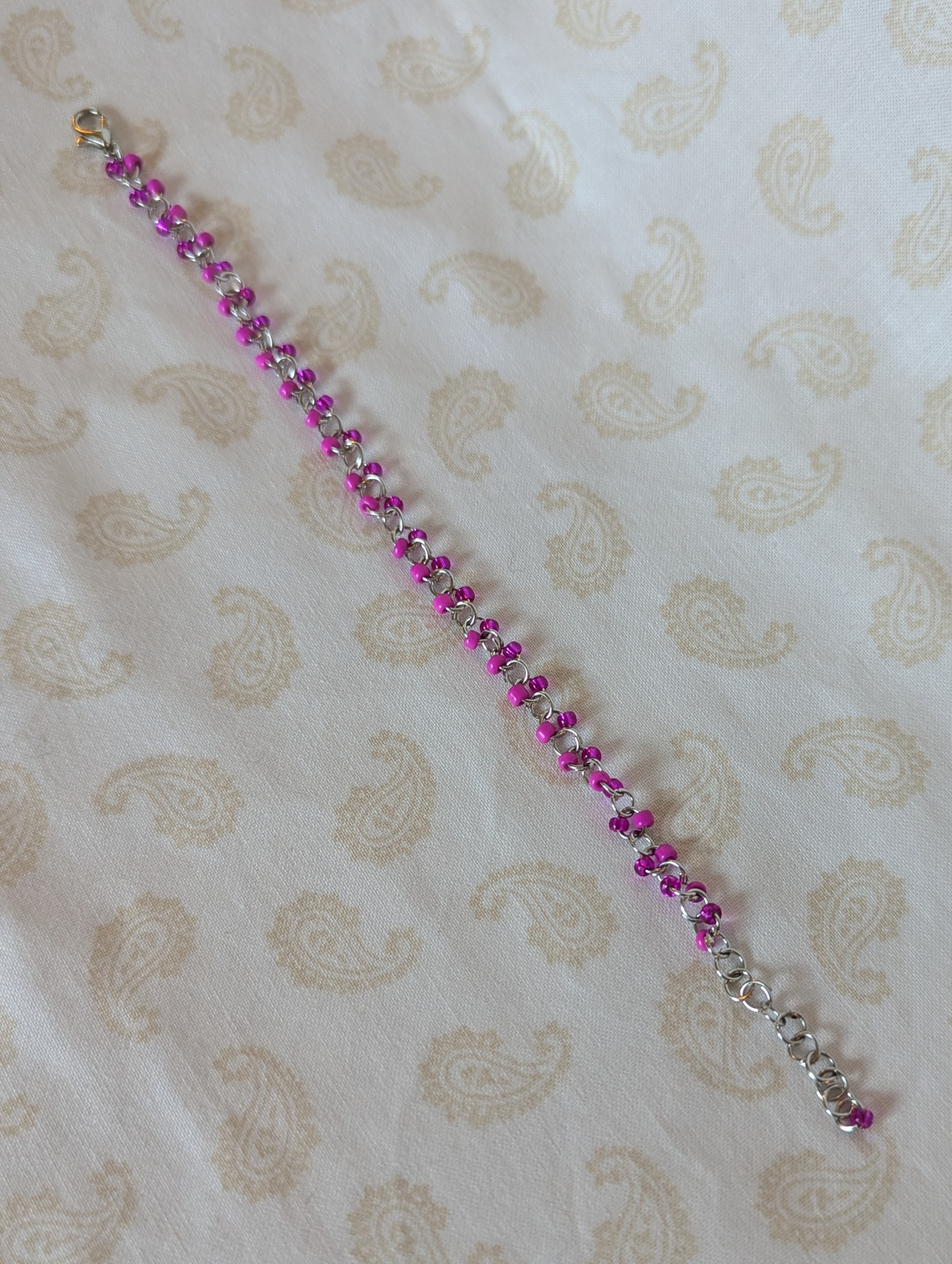 Steel-colored chain bracelet with alternating hot pink and silver-lined translucent pink glass beads and a lobster clasp.