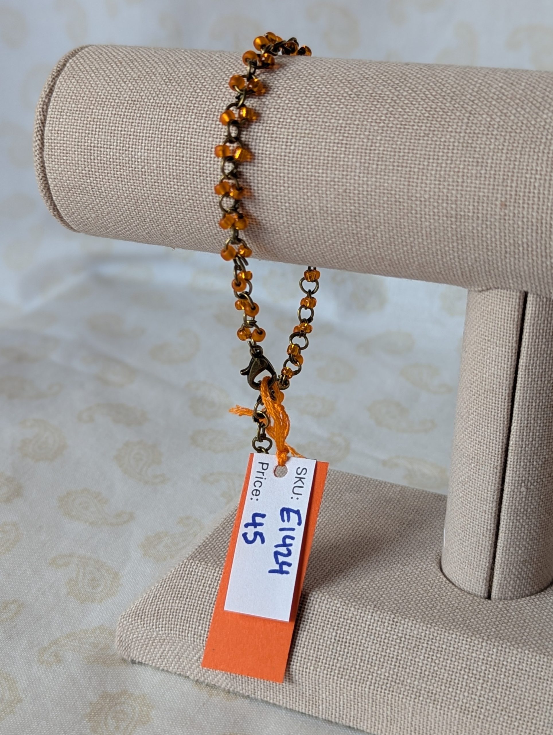 Orange seed bead bracelet with hand-linked bronze chain, matte and silver-lined orange beads, and bronze lobster clasp