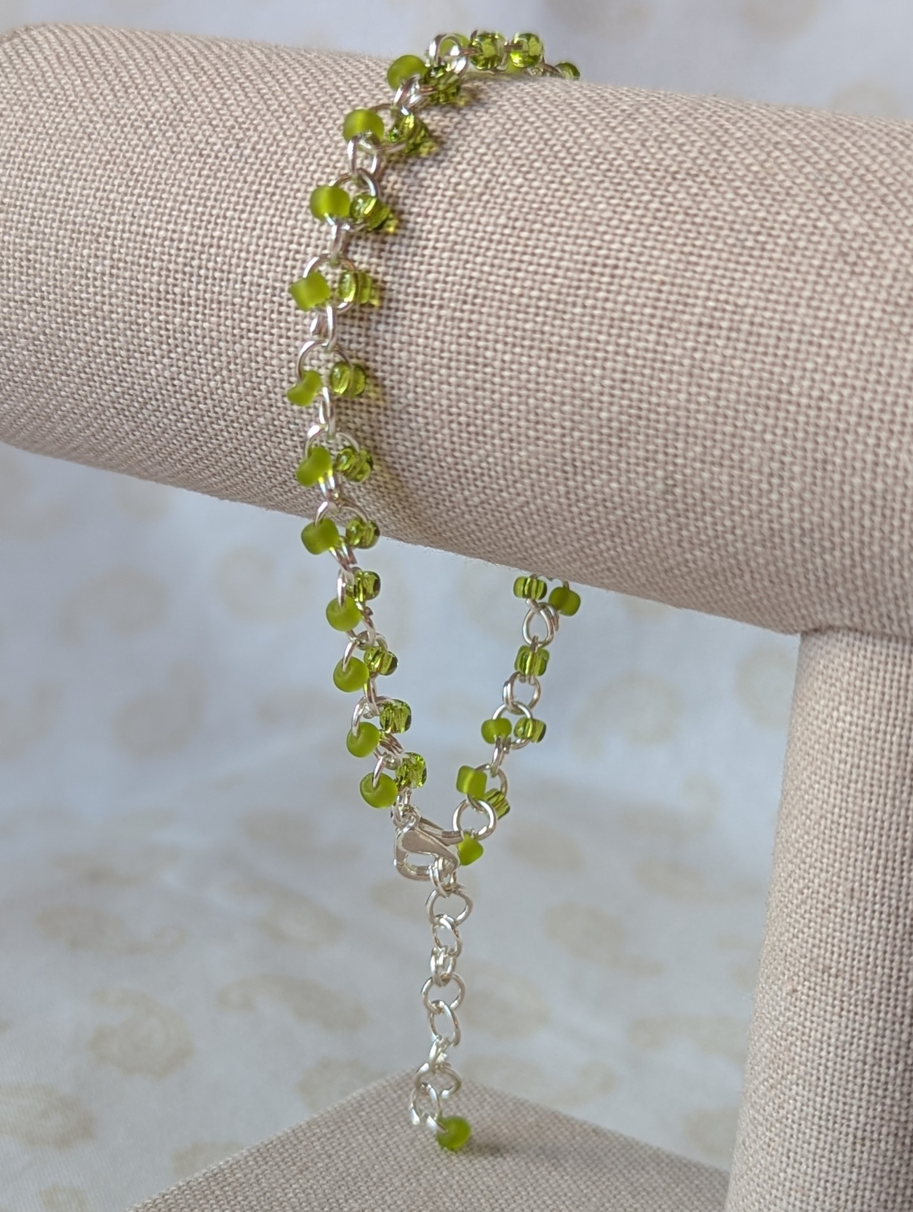 Silver-colored, hand-linked chain bracelet with paired green seed beads, featuring matte lime green and silver-lined lettuce green glass beads and a lobster clasp.