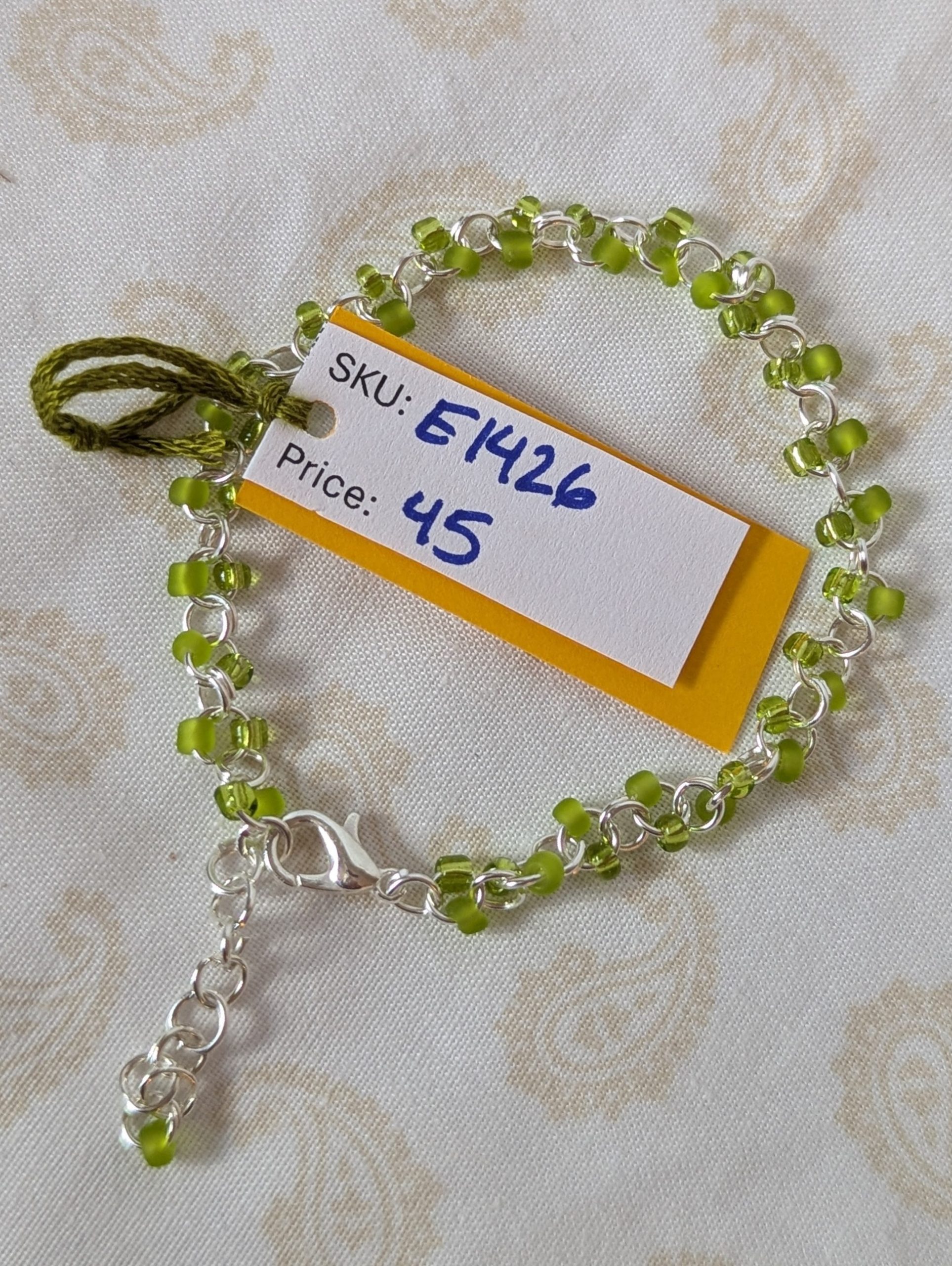 Silver-colored, hand-linked chain bracelet with paired green seed beads, featuring matte lime green and silver-lined lettuce green glass beads and a lobster clasp.