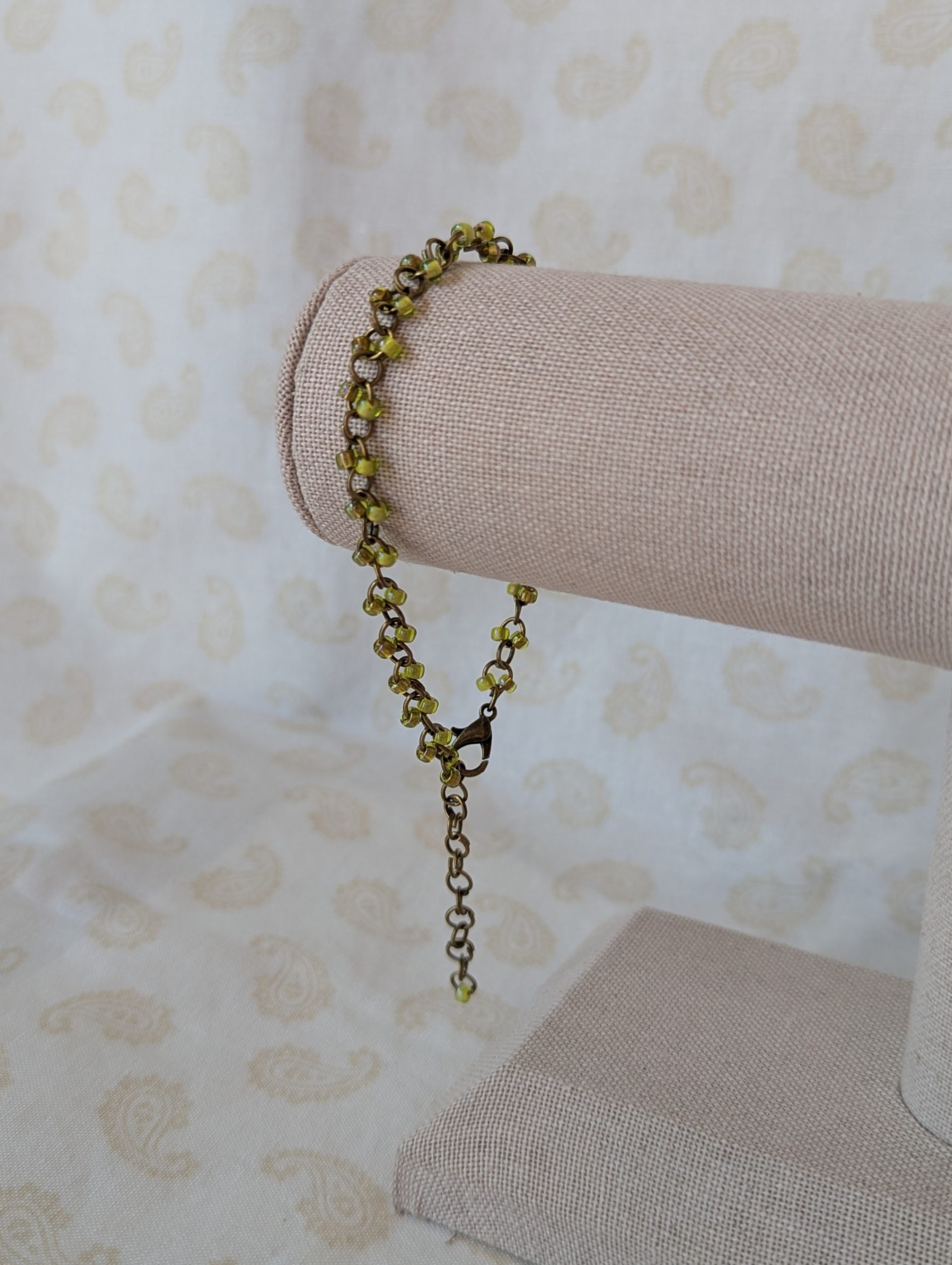 Bronze chain bracelet with paired green seed beads, featuring pink-lined green and silver-lined olive glass beads and a bronze lobster clasp.