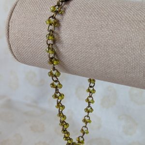Bronze chain bracelet with paired green seed beads, featuring pink-lined green and silver-lined olive glass beads and a bronze lobster clasp.