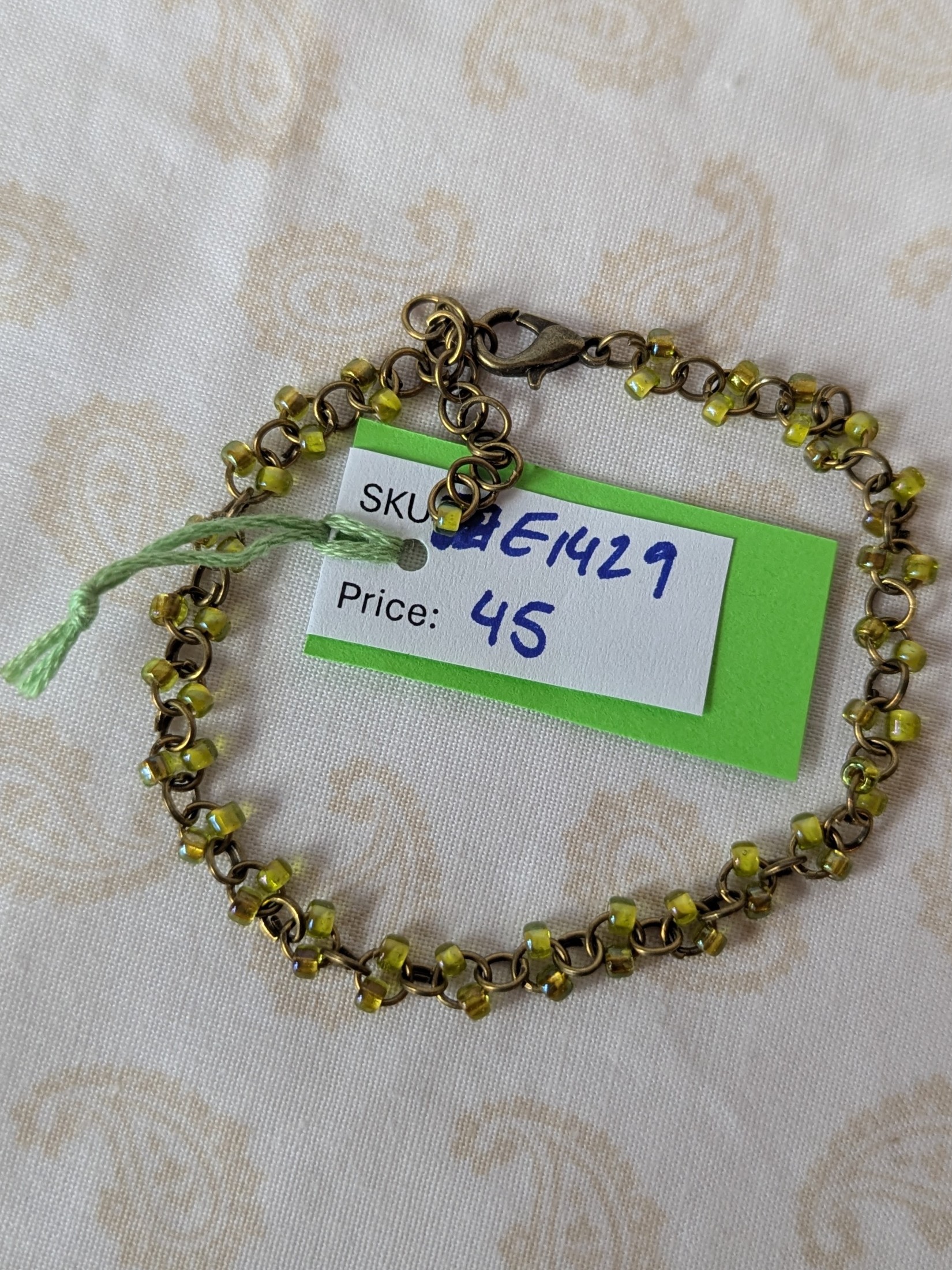 Bronze chain bracelet with paired green seed beads, featuring pink-lined green and silver-lined olive glass beads and a bronze lobster clasp.