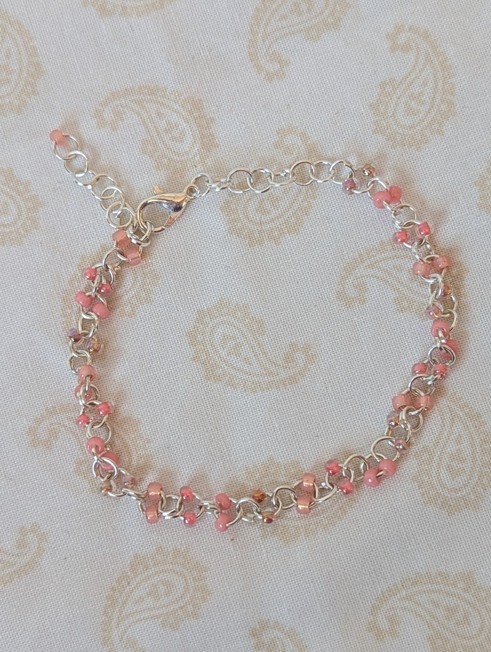 Blush and Petal Pink Beaded Chain Bracelet: a silver chain bracelet with pale pink seed beads in solid blush, pink-lined clear, and pearly iridescent finishes, secured with a lobster clasp.