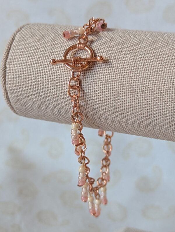 Handmade pink ombre beaded copper chain bracelet with pale blush and rose gradient seed beads and copper toggle clasp.