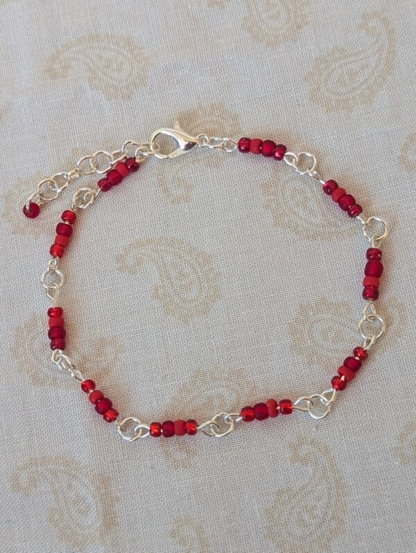 Handmade ruby red seed bead bracelet with silver chain links and crimson glass bead clusters.