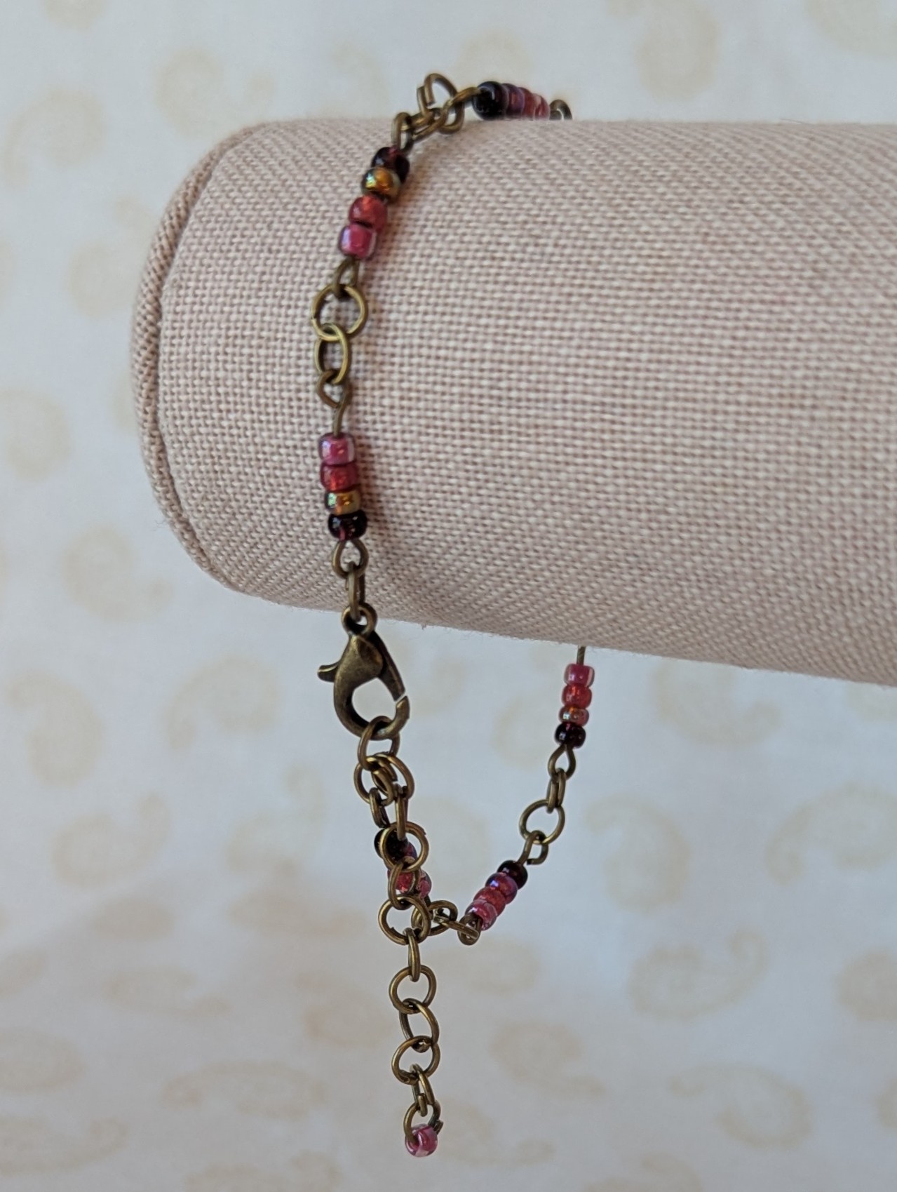 Handmade deep red gradient seed bead bracelet with bronze chain links and maroon and wine red glass bead clusters.