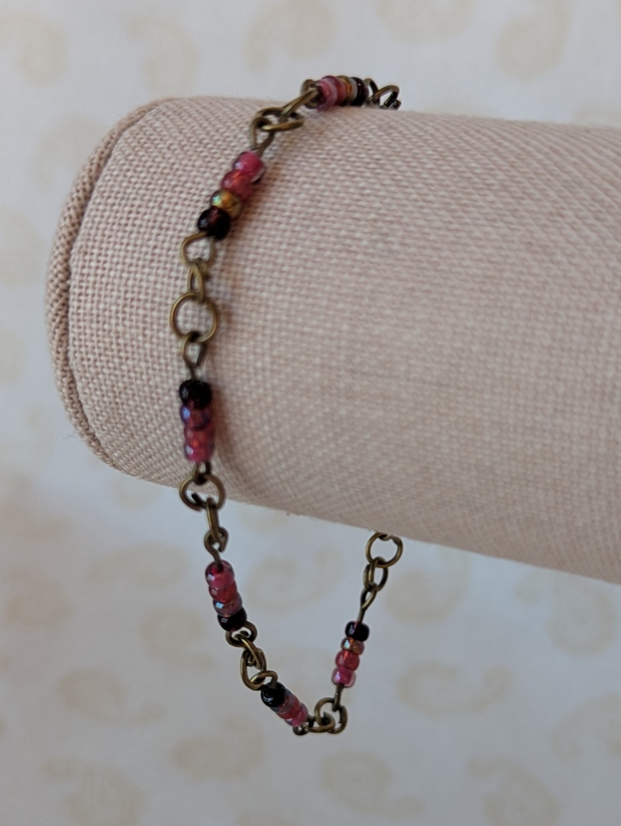 Handmade deep red gradient seed bead bracelet with bronze chain links and maroon and wine red glass bead clusters.