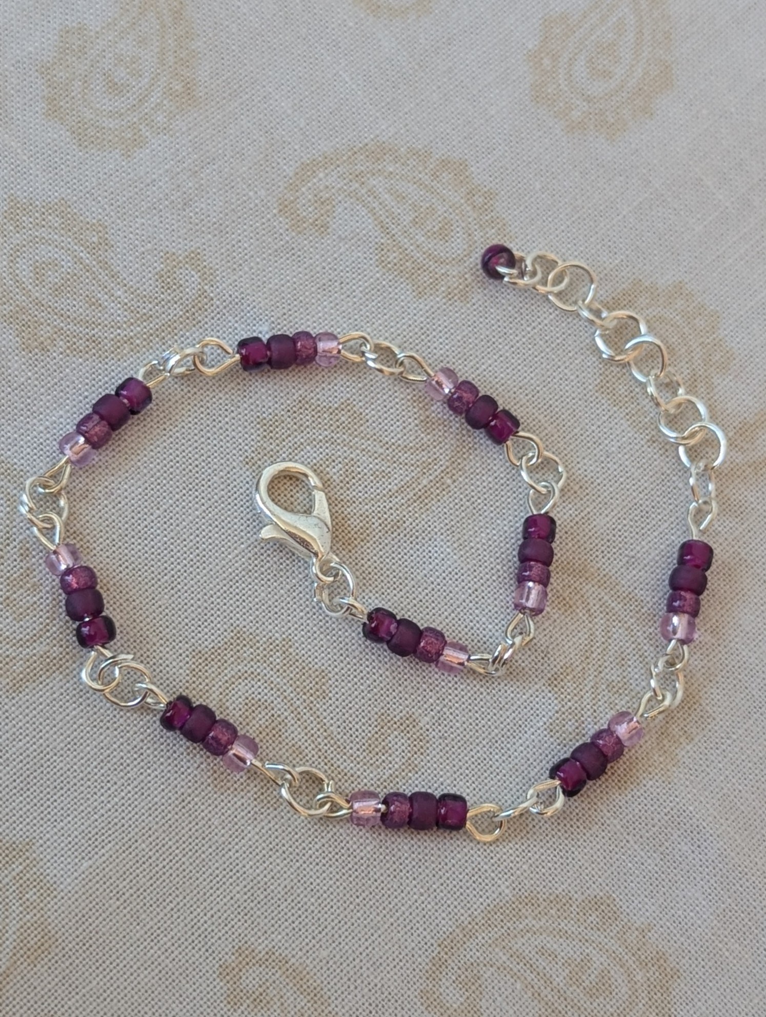Silver-toned chain bracelet with gradient purple glass seed beads in lilac, lavender, and plum tones