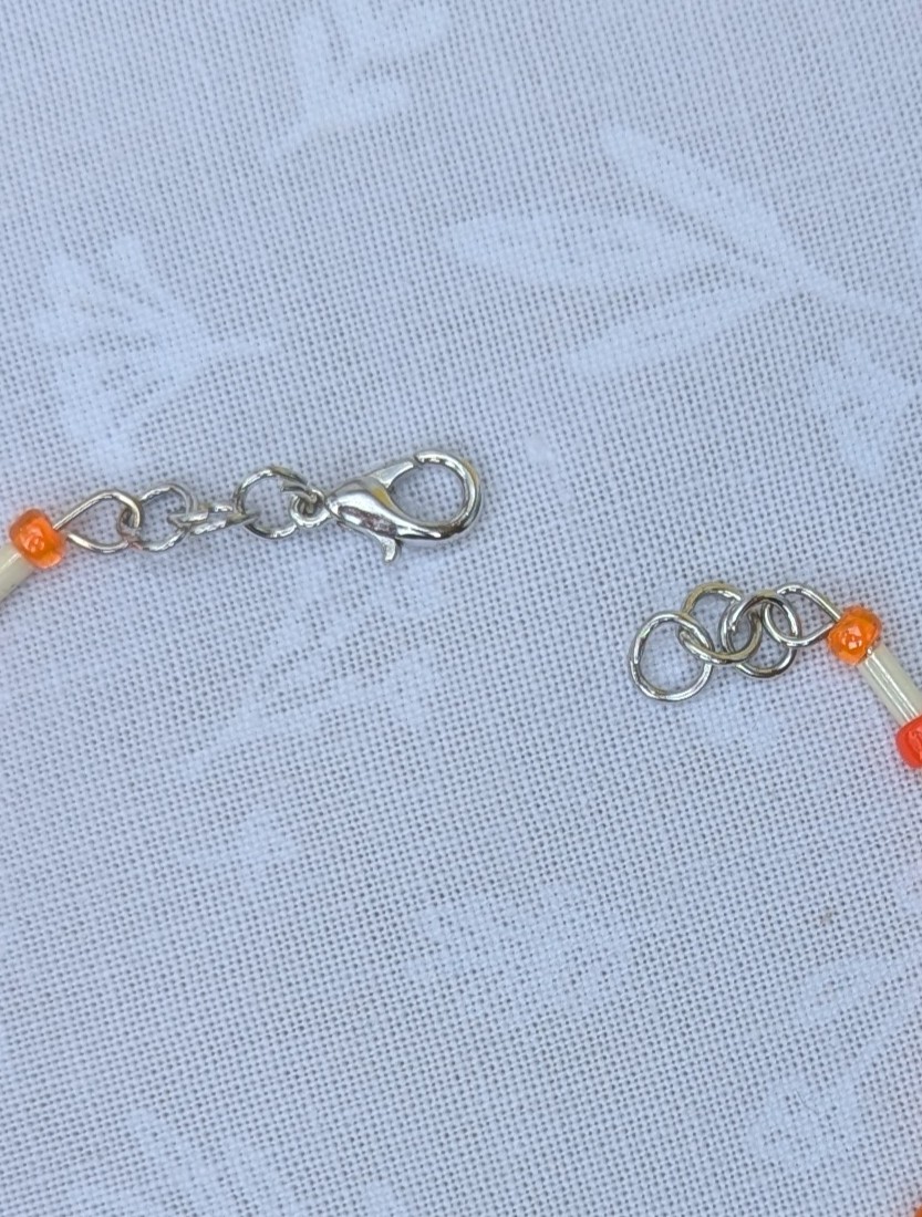 Handmade bracelet featuring cream bugle beads, vibrant orange seed beads, and a wire-wrapped Murano glass bead centerpiece on linked steel-colored memory wire with lobster clasp closure.