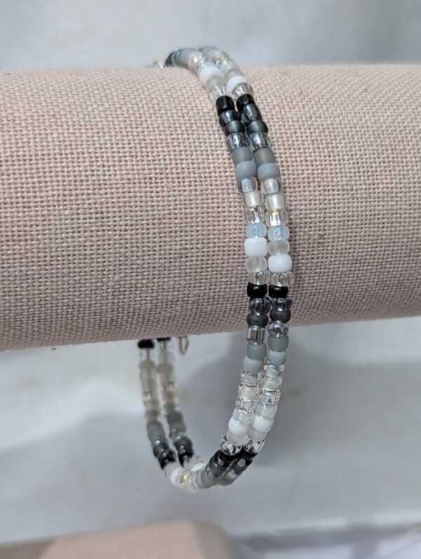 Monochrome gradient memory wire bracelet with black, gray, silver, and frosted white glass seed beads wrapped around wrist.