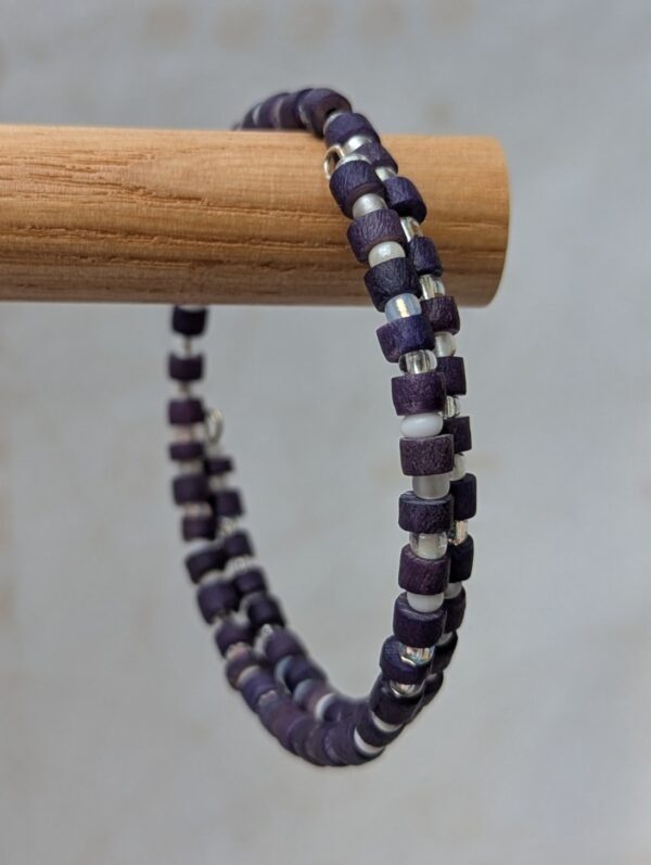 Multi-wrap steel-toned memory wire bracelet with deep indigo wooden beads and frosted white and iridescent clear accent beads in a clasp-free spiral design.