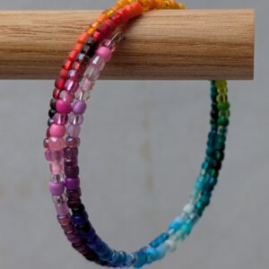 2.25-wrap rainbow memory wire bracelet with multicolored translucent, frosted, and iridescent beads on steel-toned wire in a clasp-free spiral design.
