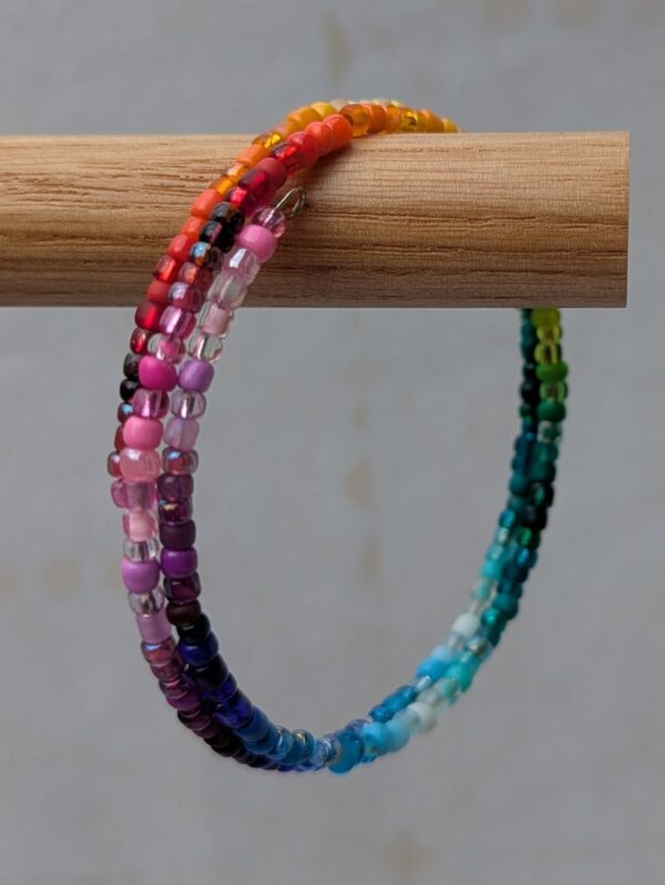 2.25-wrap rainbow memory wire bracelet with multicolored translucent, frosted, and iridescent beads on steel-toned wire in a clasp-free spiral design.