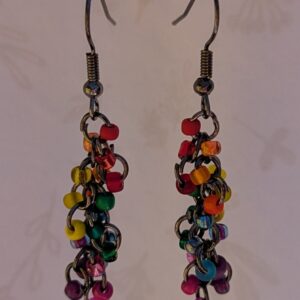 Handmade rainbow fringe earrings with multicolored glass beads and bronze jump rings hanging from bronze French earring hooks.