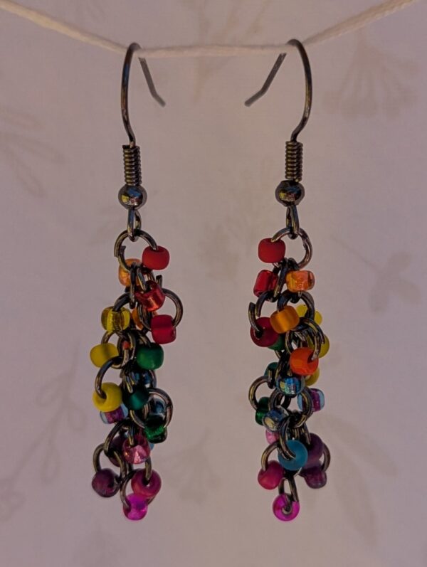 Handmade rainbow fringe earrings with multicolored glass beads and bronze jump rings hanging from bronze French earring hooks.