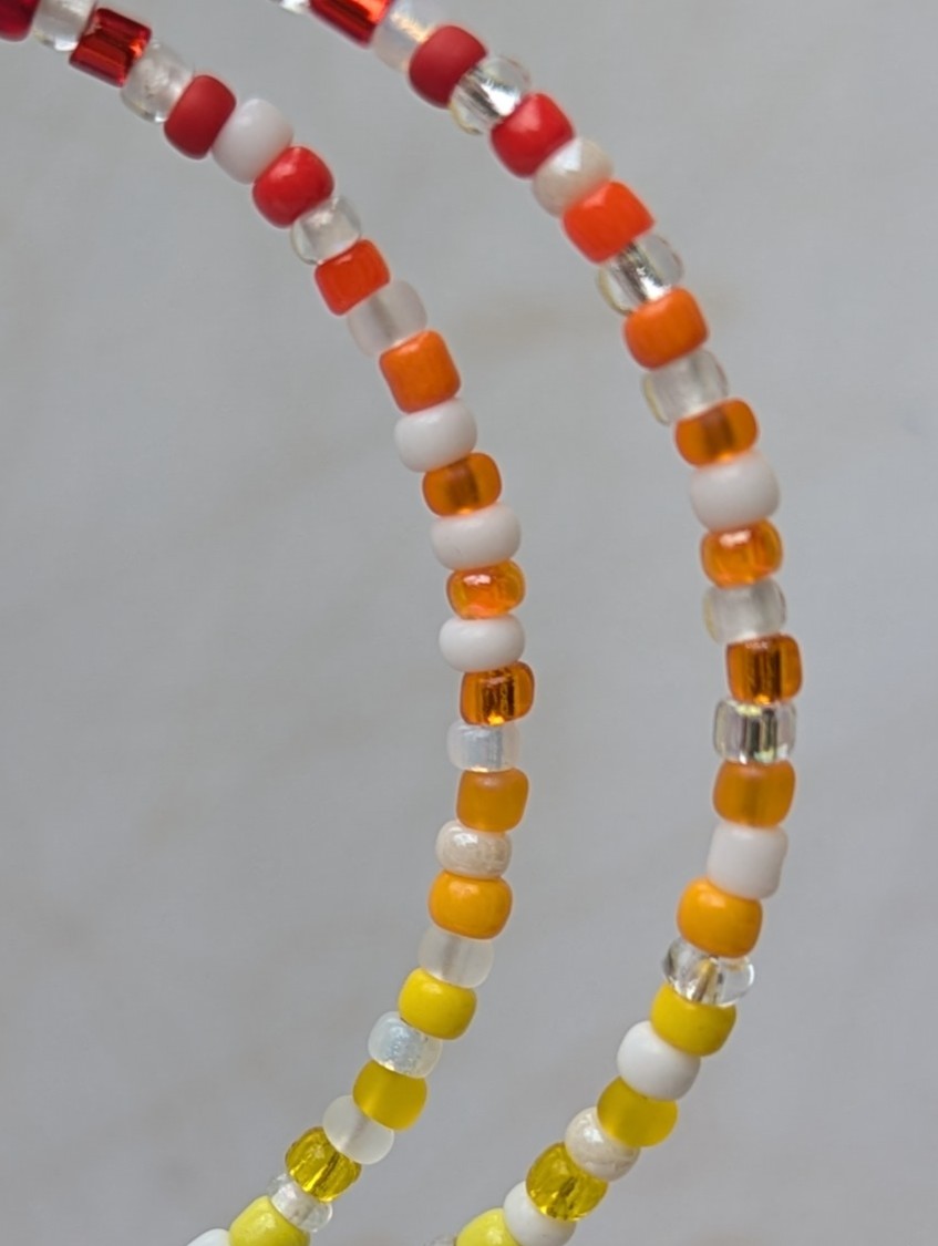 Handmade rainbow and white hoop earrings with silver-colored memory wire, multicolored glass seed beads, white and clear accent beads, and sterling silver French hooks.