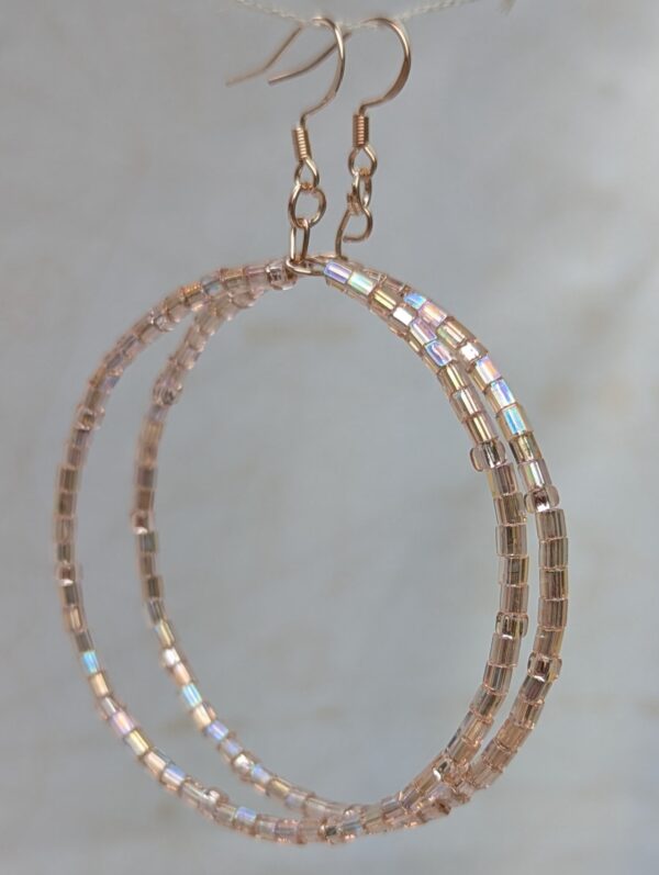 Handmade rose gold hoop earrings with pale pink silver-lined beads in hexagonal and round shapes on rose-gold-colored French hooks.