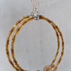 Handmade brown hoop earrings with steel-colored memory wire, amber and cocoa glass beads, tan focal beads, and sterling silver French hooks.