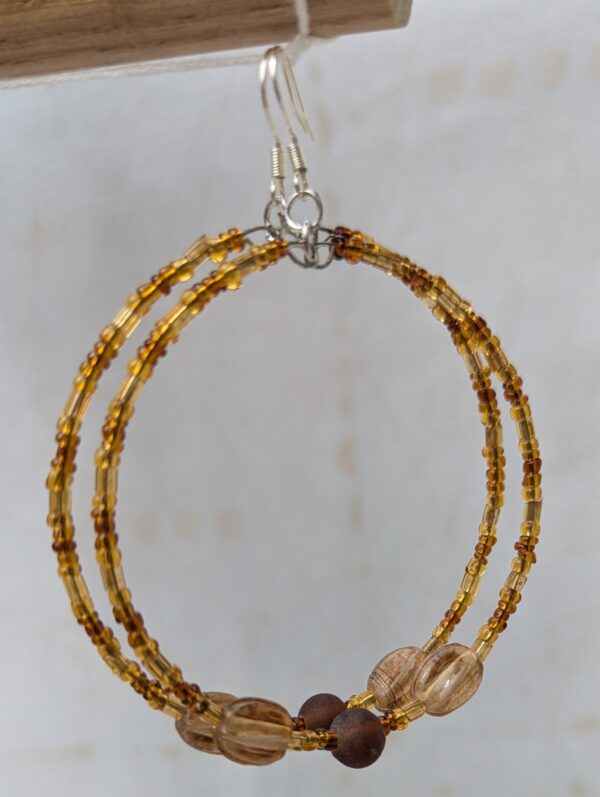 Handmade brown hoop earrings with steel-colored memory wire, amber and cocoa glass beads, tan focal beads, and sterling silver French hooks.