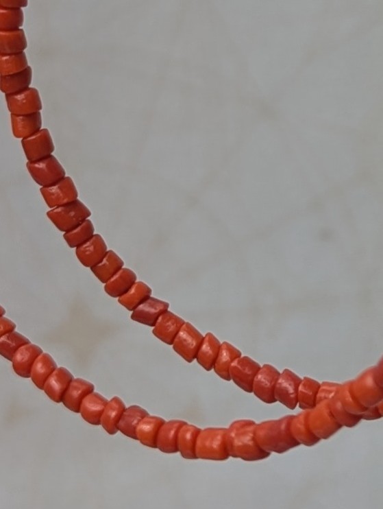 Handmade coral red beaded hoop earrings on bronze-colored memory wire with matching bronze French hooks.
