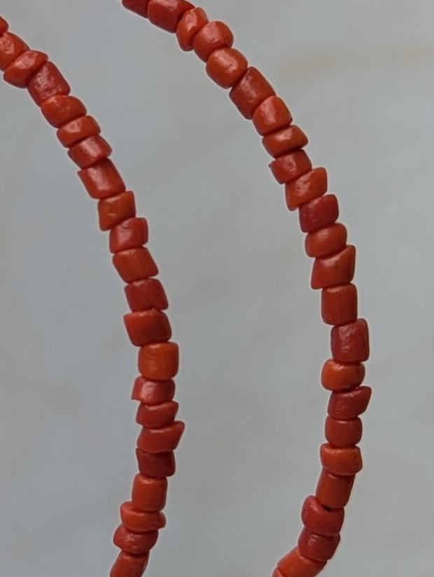 Handmade coral red beaded hoop earrings on bronze-colored memory wire with matching bronze French hooks.