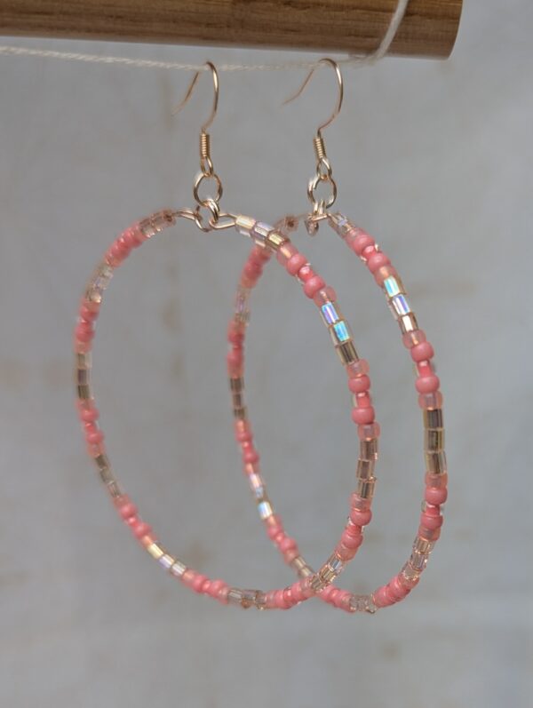 Handmade pale pink beaded hoop earrings with iridescent silver-lined beads on rose-gold-colored memory wire and matching French hooks.
