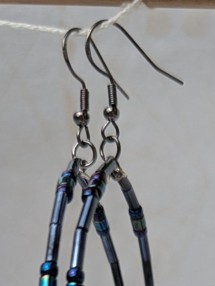 Handmade blue-black metallic hoop earrings with iridescent glass beads on steel-colored memory wire and tungsten-colored French hooks.