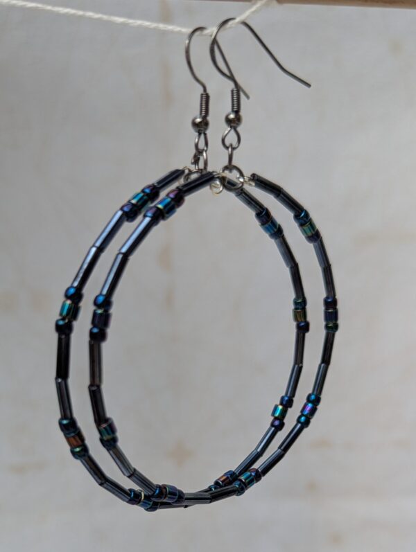 Handmade blue-black metallic hoop earrings with iridescent glass beads on steel-colored memory wire and tungsten-colored French hooks.
