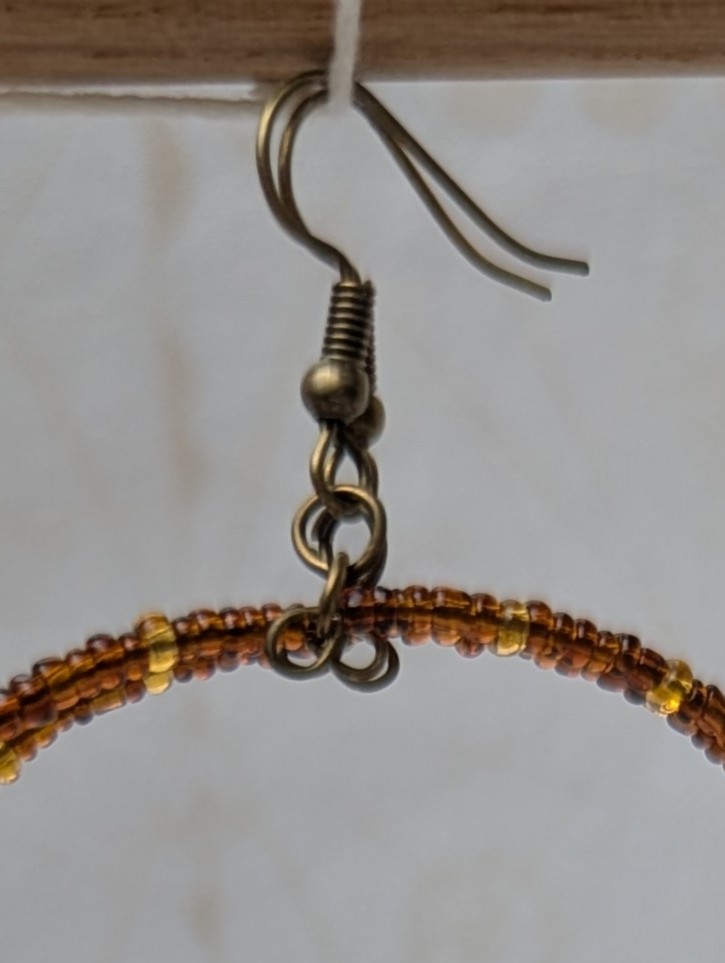 Handmade bronze memory wire hoop earrings with chestnut brown and honey amber glass seed beads and bronze French hooks.