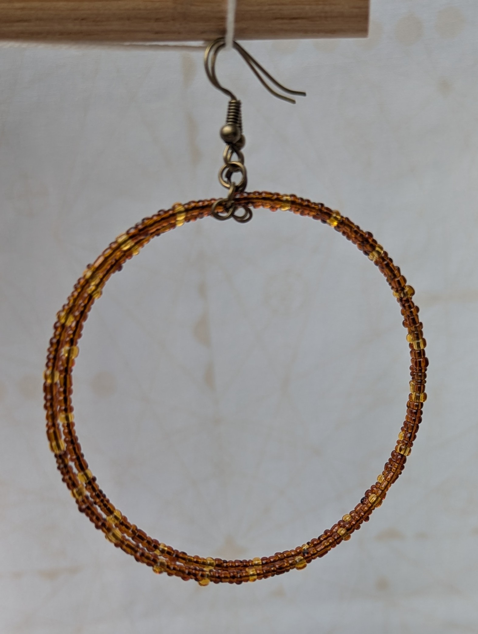 Handmade bronze memory wire hoop earrings with chestnut brown and honey amber glass seed beads and bronze French hooks.