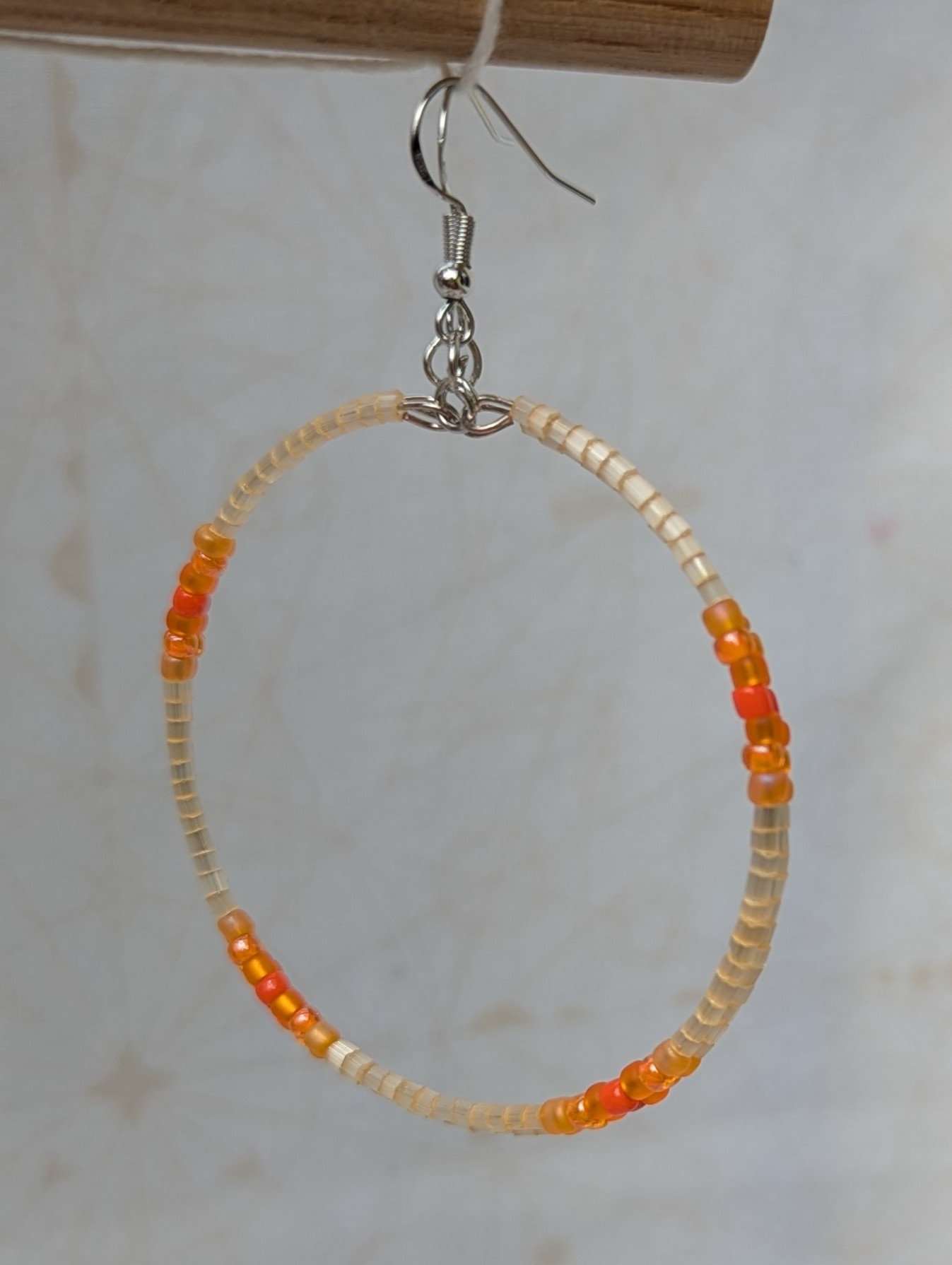 Handmade rose gold hoop earrings with ivory, amber, apricot, coral orange, and tangerine glass beads on memory wire with matching French hooks.