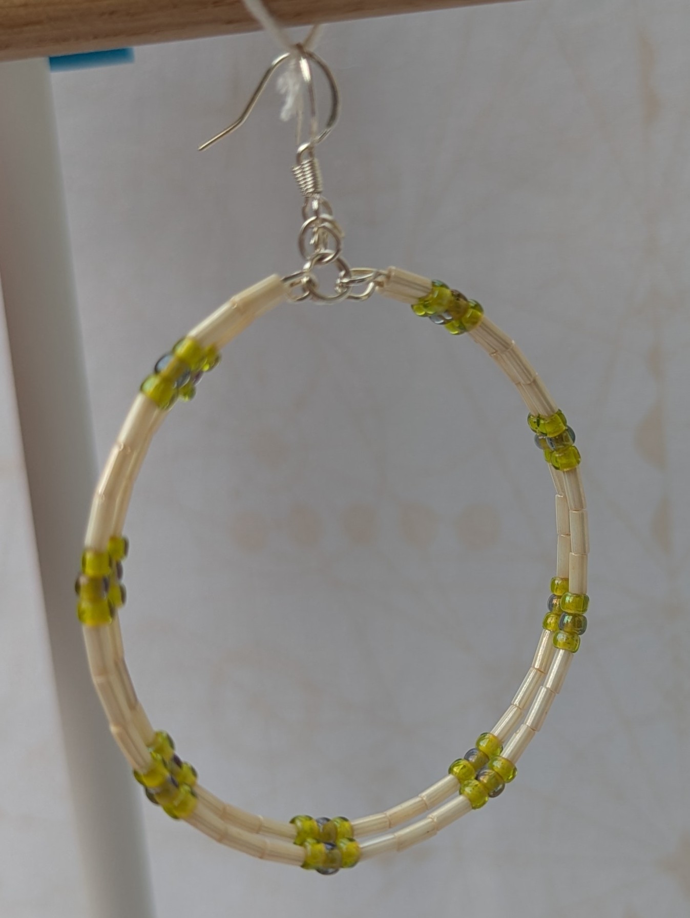 Handmade silver memory wire hoop earrings with creamy ivory tube beads and lime, moss, and chartreuse green glass bead accents on sterling silver hooks.