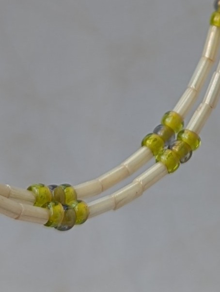 Handmade silver memory wire hoop earrings with creamy ivory tube beads and lime, moss, and chartreuse green glass bead accents on sterling silver hooks.