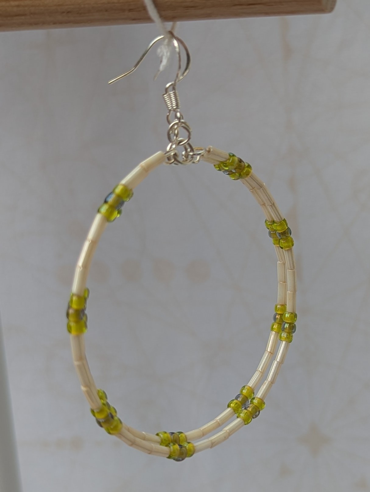 Handmade silver memory wire hoop earrings with creamy ivory tube beads and lime, moss, and chartreuse green glass bead accents on sterling silver hooks.