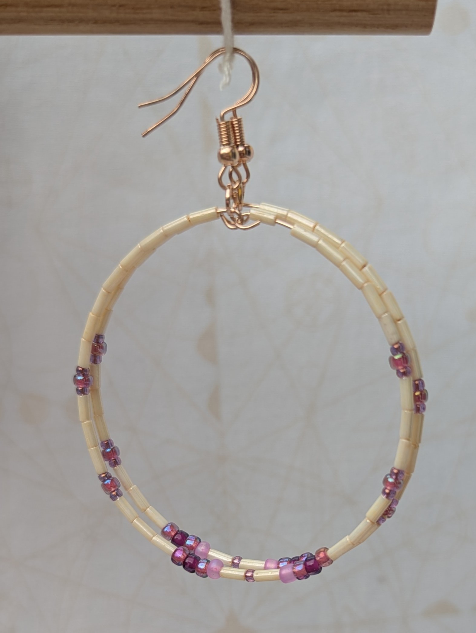Handmade rose gold hoop earrings with ivory tube beads and lavender, mauve, plum, and orchid purple glass bead accents on rose gold French hooks.