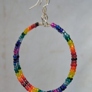 Handmade rainbow gradient hoop earrings with multicolored glass seed beads on silver memory wire and sterling silver French hooks.