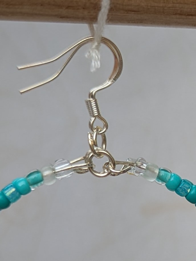 Handmade teal gradient hoop earrings with aqua, turquoise, and ocean-blue glass beads on silver memory wire and sterling silver French hooks.